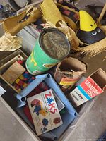 Plastic tote containing green cylinder, blue bin with Zaks pieces, Lincoln Logs box, Canadian Logs box, straw figure