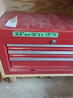 Front view of red tool chest showing three of four drawers and dimensions label