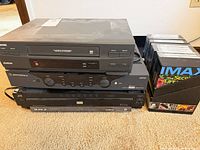 Stacked Toshiba VCR, Motorola box, JVC DVD changer, DVD collection in stand
