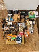 Overhead view of entire lot showing cameras, film, cassette player, Sega cartridge, chargers and accessories