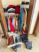 Closet view with hanging and folded clothing, shoes on shelf, bags and shoes on floor boxes