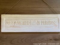 Front of whitewashed wooden sign showing raised lettering