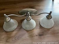 Front view of brushed nickel three-light vanity fixture with frosted glass shades