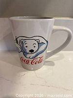 Front of white ceramic mug with polar bear graphic and Coca-Cola logo