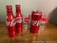 Front view of two aluminum bottles, one aluminum can, and two plastic tumblers