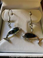 Front view of dolphin earrings with blue paua shell in box