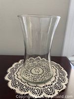Front view of clear glass vase on lace doily