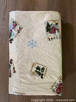 Folded cream vinyl tablecloth showing holiday motif
