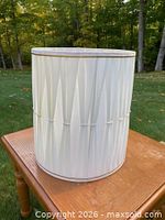 Full view of white pleated cylindrical lampshade on table