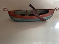 Side view of painted metal boat candle holder