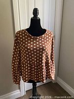 Front view of caramel polka-dot peplum sweater on dress form