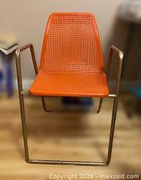 Front view of orange plastic mesh chair showing seat, backrest and tubular frame
