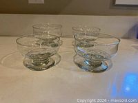 Four glass footed bowls arranged on countertop
