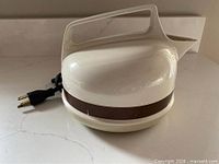 Side view of cream plastic kettle showing brown band and cord