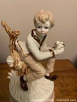 Front view of porcelain music box showing boy figurine on base