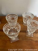 Four pressed glass goblets on wooden surface