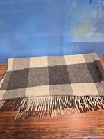 Full view of folded plaid wool shawl with fringe