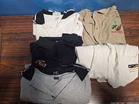 Group of five folded polo shirts showing colors and styles