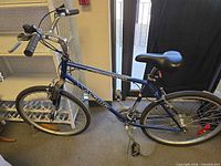 Full side view of blue hybrid bicycle showing frame, saddle, wheels and components