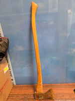 Full view of axe standing upright against wall