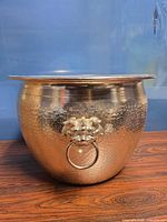 Full view of hammered silver-tone planter showing lion head handle