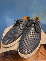 Top and side view of both shoes showing perforated leather uppers and lacing