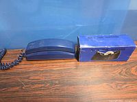 Blue GE corded telephone and boxed tape dispenser on wood surface