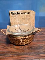 Casserole set with lid and basket in front of box