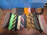 Row of neckties laid out with three rolled belts on the right