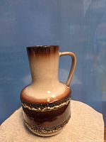 Full view of brown drip-glaze ceramic pitcher with handle
