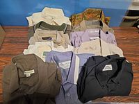 Overview of approximately twelve folded shirts showing variety of colours and styles