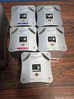 Underside of five satellite speakers showing model labels, serial numbers and color-coded terminals