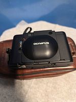 Olympus XA camera closed, top view on brown leather case