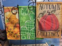 Three seasonal garden flags on display stands
