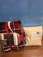 Plaid fleece throw blanket next to sealed beige South Point queen sheet set
