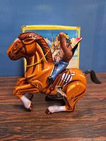 Side view of tin wind-up horse and cowboy, key visible, box in background