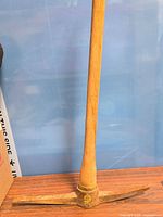 Full view of pickaxe-mattock showing wood handle and steel/iron head