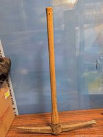 Full view of pickaxe standing upright showing complete handle and head