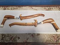 Both daggers sheathed, showing overall shape and matching wood construction