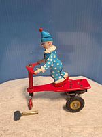 Left side view showing clown figure on red scooter and key nearby
