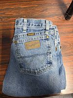 Folded jeans showing back pocket, leather Wrangler patch, overall color and style