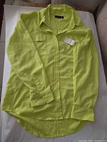 Front view of neon yellow chiffon blouse with tags attached, showing collar, chest pocket, buttons and sleeves
