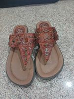 Top view of pair showing leather color, stud pattern, toe post, footbed logo