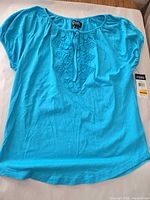 Front view of turquoise blouse with tags attached
