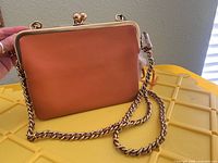 Front view of coral/peach Coach leather crossbody with gold-tone chain strap