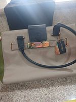 Front view of Coach beige/taupe and green leather tote with gold-tone hardware and hangtag