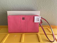 Front of pink leather Coach wristlet with tag and box