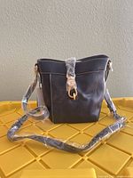 Front view of the Dooney & Bourke black leather crossbody bag with strap wrapped and hardware visible