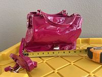 Side view of satchel with tape measure showing approx 11 inch length and detachable strap visible