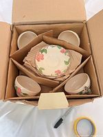 Open box showing five cups and stack of saucers